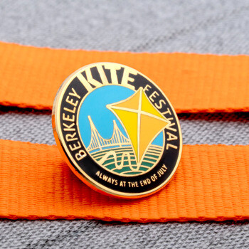 Berkeley Kite Festival lapel pin featuring a yellow kite and Golden Gate Bridge design on an orange strap.