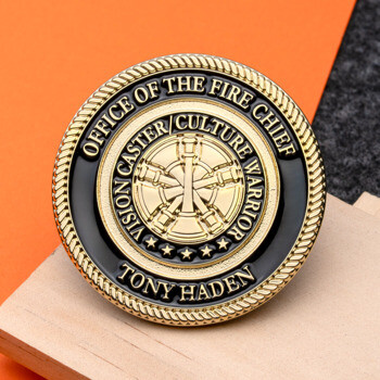 Gold and black challenge coin for the Office of the Fire Chief featuring a central fire department emblem and a rope-textured edge.