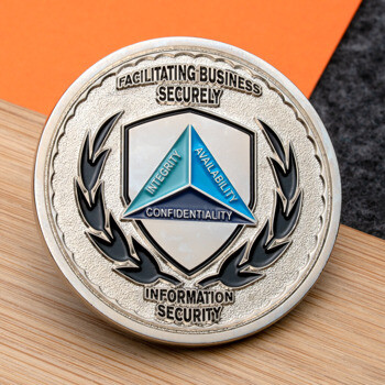 Silver challenge coin featuring a CIA triad shield with Integrity, Availability, and Confidentiality text surrounded by black laurel leaves.