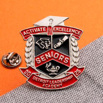 Detroit Leadership Academy Seniors 2025 crest lapel pin with graduation cap top and clutch backing on grey fabric and orange background.