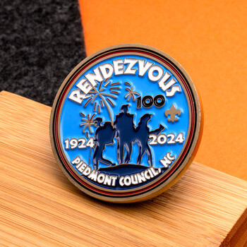 Rendezvous 100 Piedmont Council NC challenge coin with blue enamel, scout silhouettes, and celebratory fireworks.